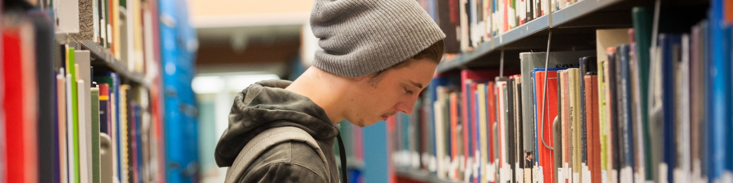 student reading a book in the library stacks