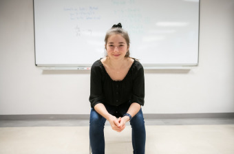 upei math graduate shannan hill sitting in front of a whiteboard